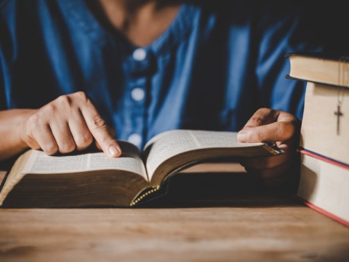 Spirituality and religion, Hands folded in prayer on a Holy Bible in church concept for faith.